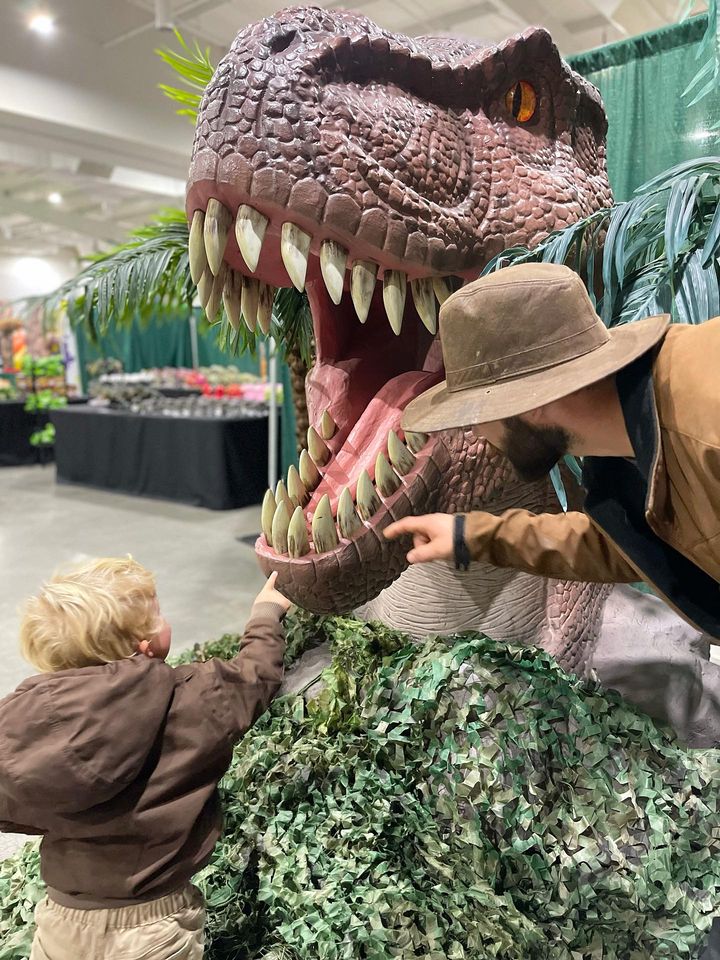 child touching dinosaur animatronics with exhibit docent